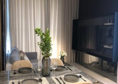 Modern living and dining area with a decorative plant and a large TV