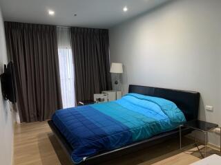 Modern bedroom with blue bedspread and dark curtains