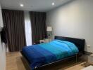 Modern bedroom with blue bedspread and dark curtains