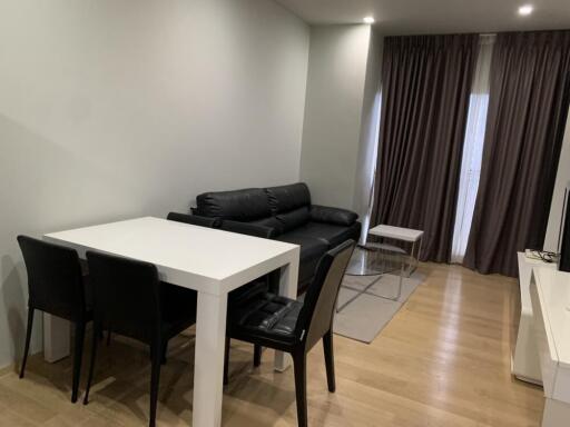 Modern living area with a dining table, couch, and large windows.