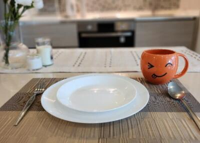 Close-up of a kitchen table setting with dishware and a cute orange mug