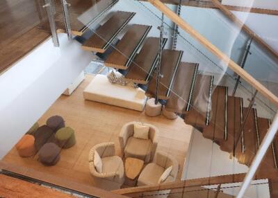 View from upper floor down to a modern living space with wooden stairs and colorful seating