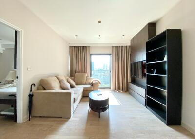 Modern living room with light wood flooring, beige sofa set, black entertainment unit, and a coffee table