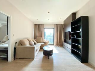 Modern living room with light wood flooring, beige sofa set, black entertainment unit, and a coffee table