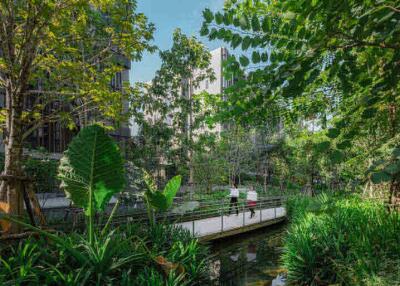 Beautiful lush garden with a bridge and buildings in the background