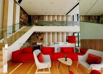 Modern living room with red and white furniture, wooden flooring, staircase and large shelving