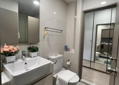 Modern bathroom with a sink, toilet, mirror, and cabinets.