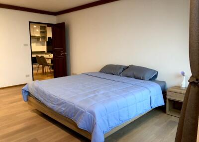 Bedroom with blue bedding and view into kitchen area