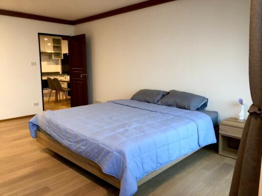 Bedroom with blue bedding and view into kitchen area