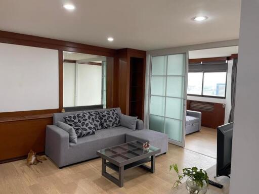 Modern living room with grey sofa, glass coffee table, and sliding glass doors