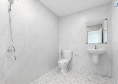 Minimalist bathroom with white tiles, wall-mounted sink, and toilet