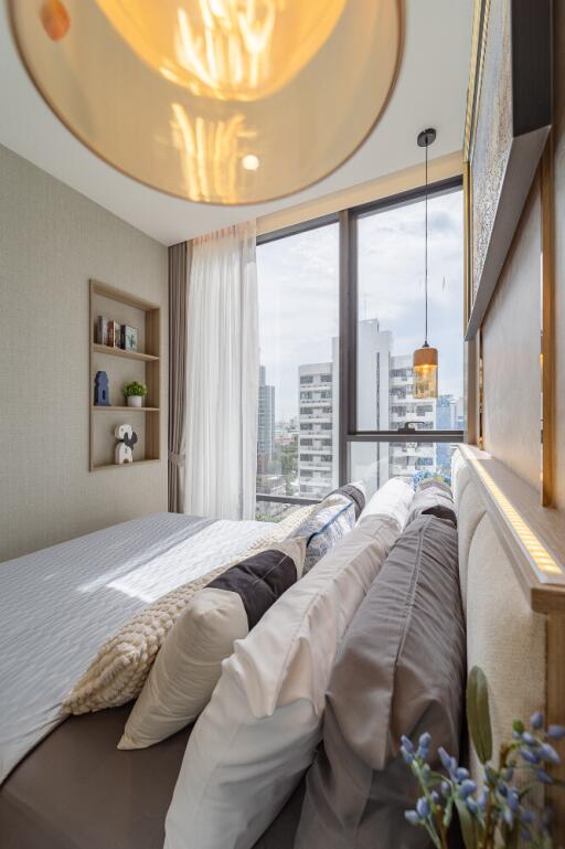 Modern bedroom with a city view, decorative pillows, and a well-lit ambiance