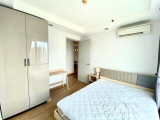 Bright and modern bedroom with white walls, wood flooring, and a large wardrobe