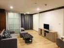 Modern living room with wooden flooring, TV unit, gray sofa, and sliding glass doors