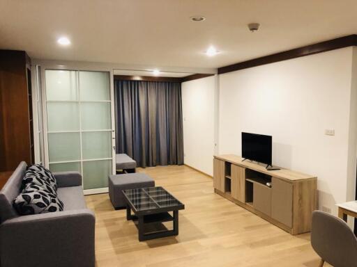 Modern living room with wooden flooring, TV unit, gray sofa, and sliding glass doors