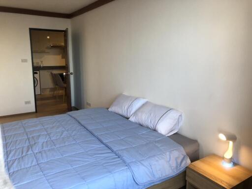 Bedroom with blue bedding and view into kitchen