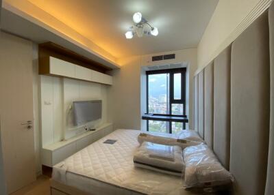 Bedroom with large window and mounted TV