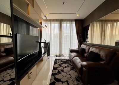 A modern living room with large windows, a leather sofa, and a flat-screen TV.