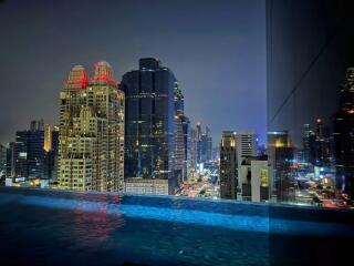 Night view of the city from a high-rise building with a pool