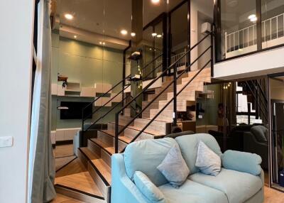 Modern living room with a staircase and blue sofa