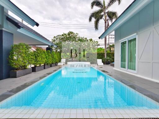 Outdoor pool with surrounding greenery and modern house