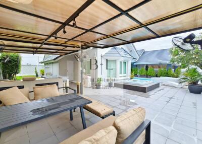 Covered outdoor patio area with seating and a view of a hot tub