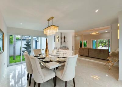 Spacious dining area with a luxurious chandelier and adjacent living room.