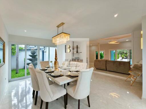 Spacious dining area with a luxurious chandelier and adjacent living room.