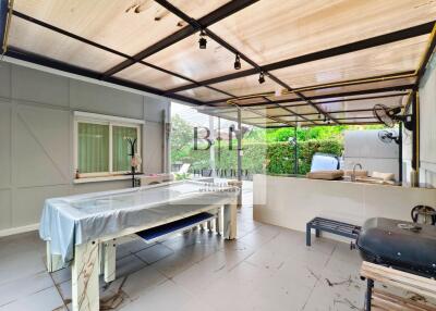 Covered outdoor area with pool table and outdoor kitchen