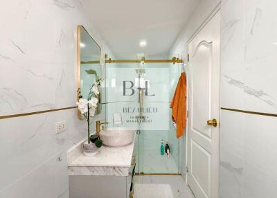 Modern bathroom with marble walls, glass shower, and vanity