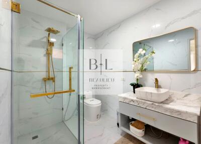 Modern bathroom with glass shower, marble sink, and elegant fixtures