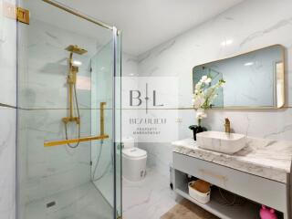 Modern bathroom with glass shower, marble sink, and elegant fixtures