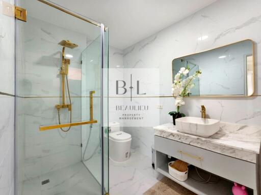 Modern bathroom with glass shower, marble sink, and elegant fixtures