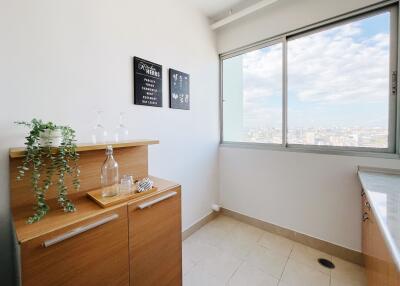 Bright kitchen area with wooden cabinets and a large window offering city views