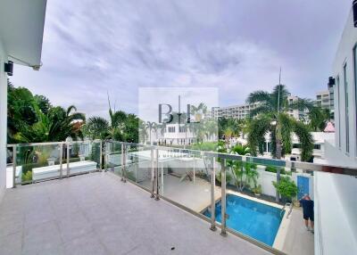 Spacious balcony with glass railing overlooking pool and garden area