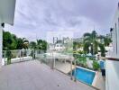 Spacious balcony with glass railing overlooking pool and garden area