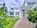 Modern white two-story house with large windows, garden, and pool