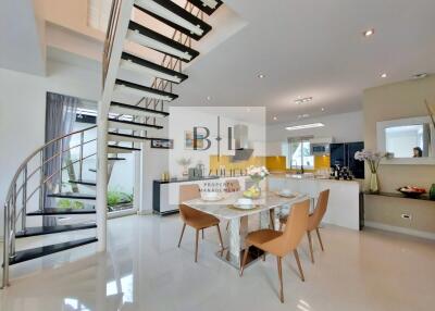 Modern living area with dining table, kitchen, and spiral staircase