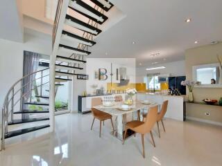 Modern living area with dining table, kitchen, and spiral staircase