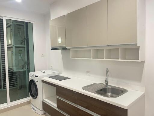 Modern kitchen with washing machine, sink, and cabinetry