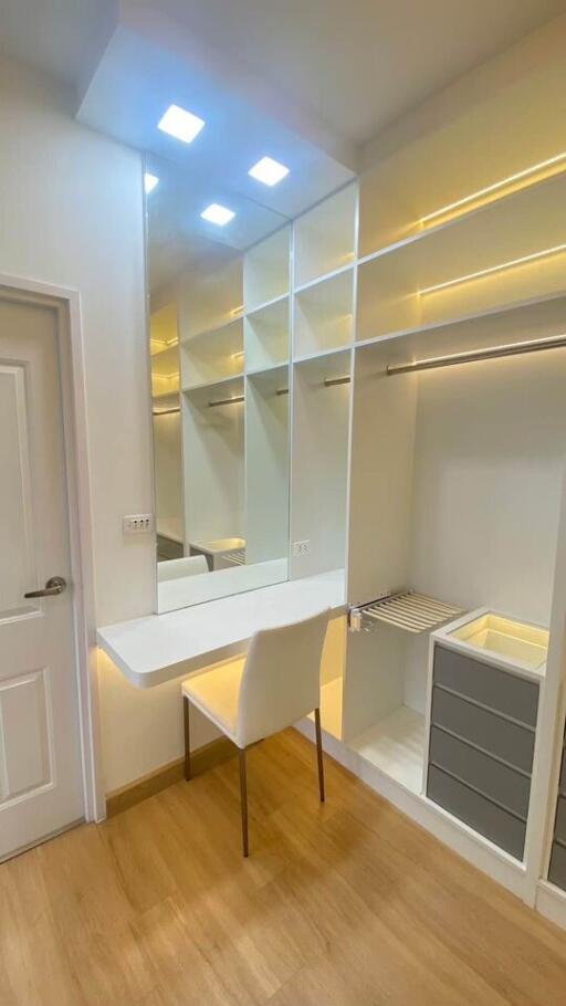 Well-lit modern walk-in closet with seated vanity area