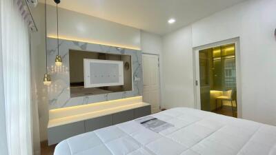 Modern bedroom with bed, lit mirror, and wardrobes