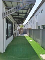 Modern backyard space with artificial grass and covered patio