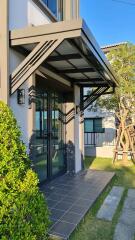 Modern house main entrance with glass door and overhang