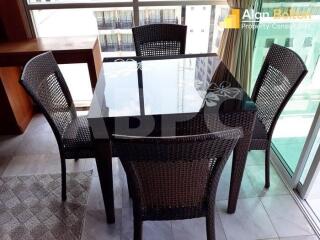 Dining area with glass-top table and four wicker chairs