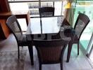 Dining area with glass-top table and four wicker chairs