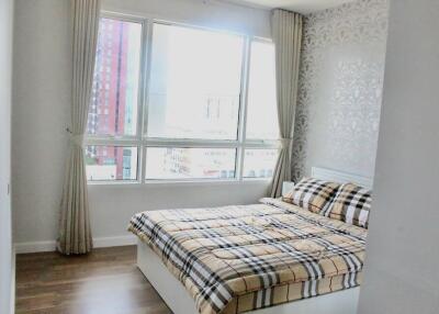 Bright bedroom with large window and patterned bedspread