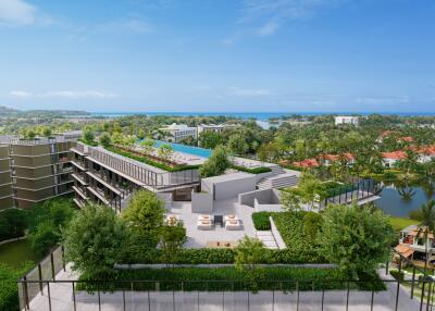 Aerial view of modern residential complex with abundant greenery and ocean in the background