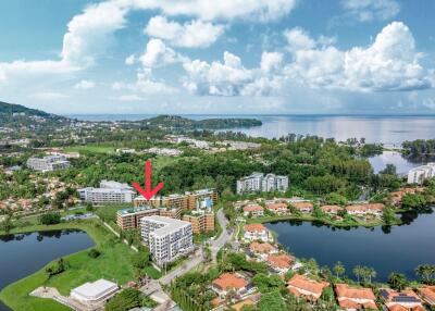 Aerial view of a residential building complex surrounded by greenery and water