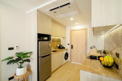 Modern kitchen with light wood cabinetry, appliances, and marble countertops